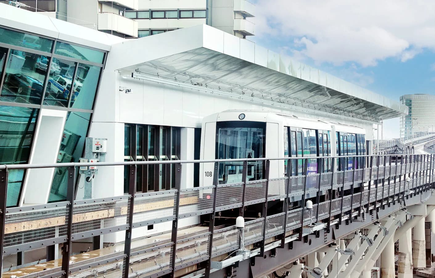 SkyLine Bahn am erhöhten Bahnsteig am Flughafen Frankfurt, weißer automatischer Stadtbahnzug an moderner verglaster Station.