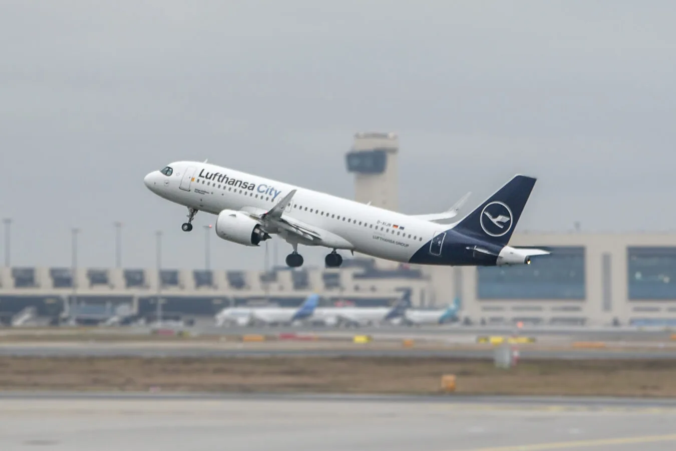 Lufthansa City Airbus A320 beim Start vom Flughafen vor Terminal und Tower