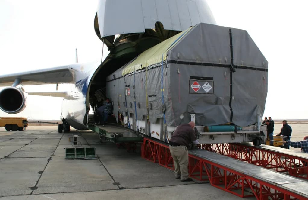 Frachtflugzeug mit geöffneter Nase beim Verladen einer großen luftfracht-Unitload-Container auf Rollbahn am Flughafen