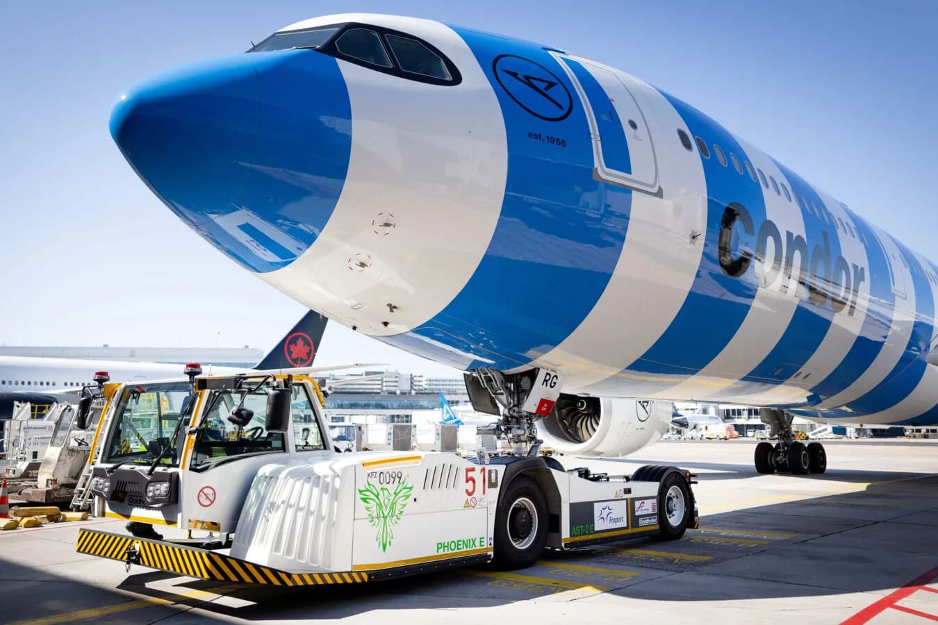 EcoTow31 Flugzeugschlepper verbindet blau-weiß lackierte Condor Passagiermaschine am Vorfeld, Nahaufnahme von Bug, Bugrad und Schlepperfahrzeug beim Bodenhandling