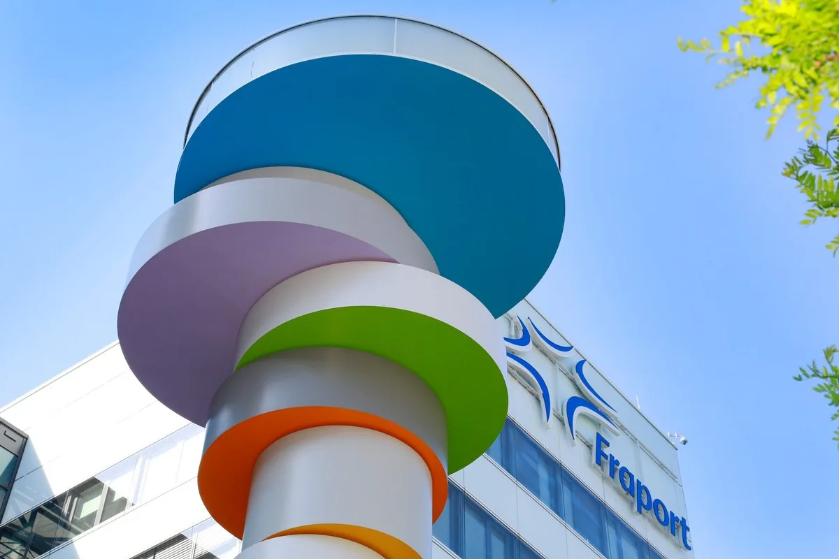 Bunte runde Skulptur aus übereinander gestapelten Scheiben vor dem Fraport-Gebäude bei klarem Himmel