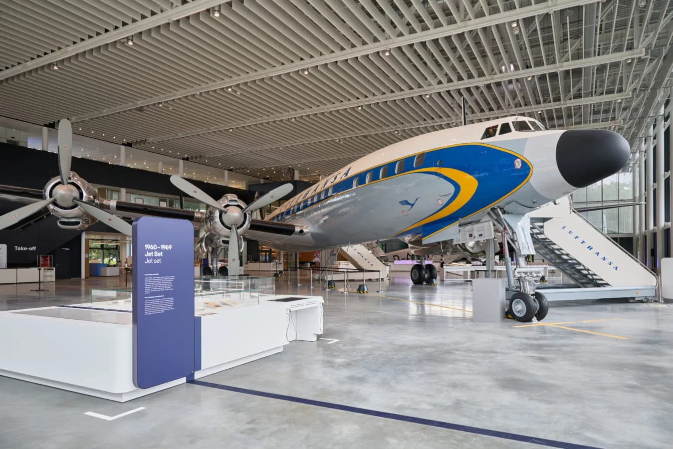 Großes Lufthansa Propellerflugzeug in modernem Experience Hangar Museum mit Ausstellungsständen und Gangway, Nahaufnahme des Bugbereichs und Triebwerke (c) Bild Lufthansagroup