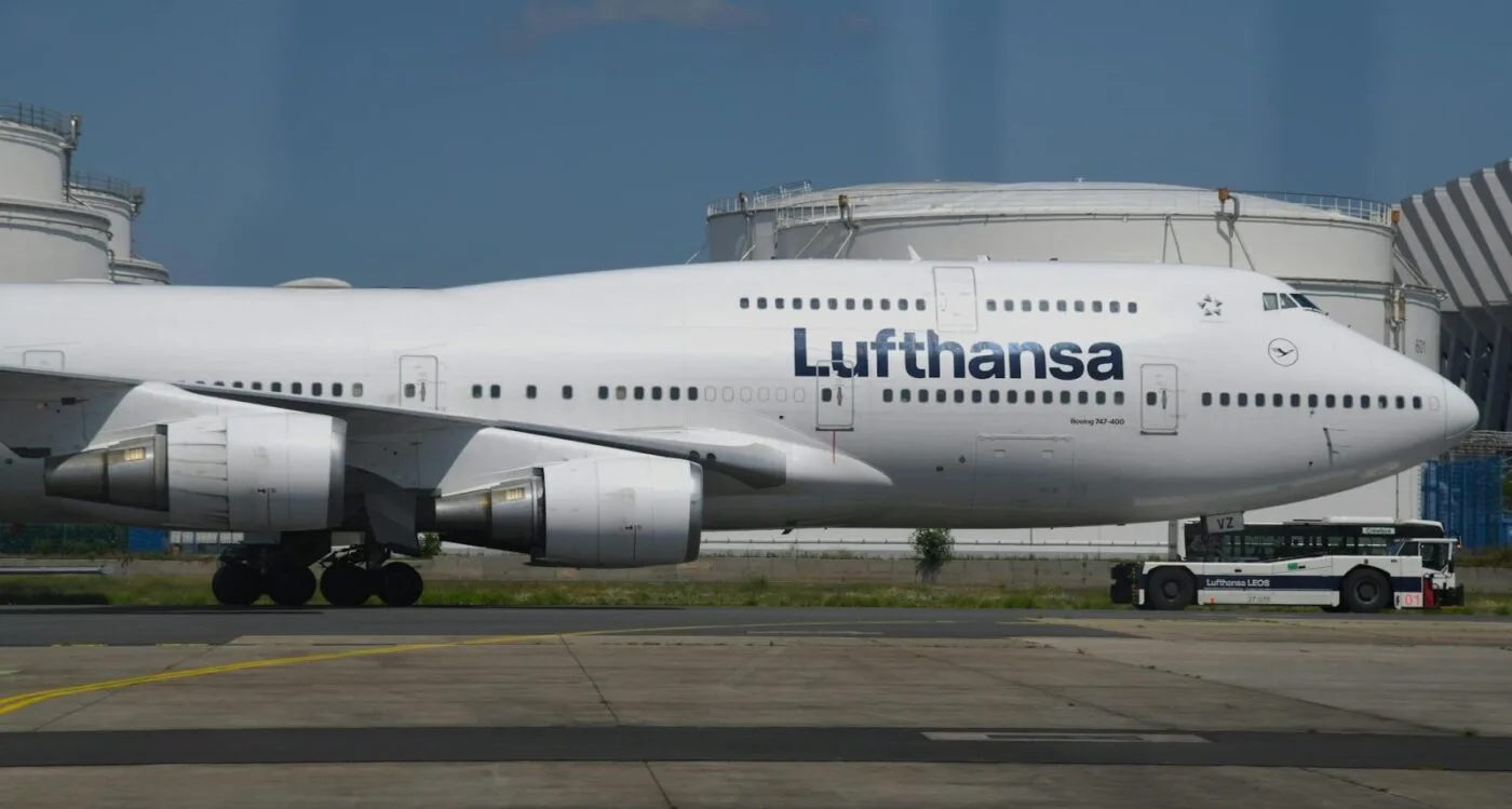 Boeing 747 von Lufthansa am Flughafen rollend, Nahaufnahme Rumpf mit Logo und Triebwerken, Vorfeldfahrzeug daneben