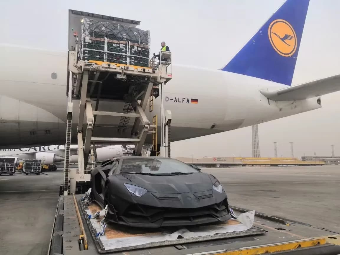 Lamborghini Aventador in matte schwarzer Folierung beim Verladen in Frachtflugzeug mit Lufthansa-Heckleitwerk auf Rollfeld