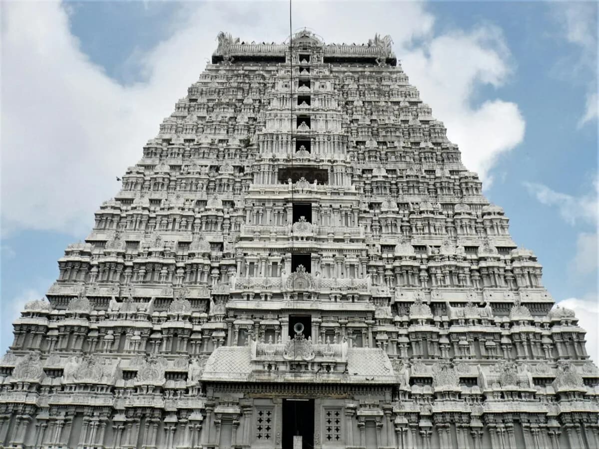 Weißer, reich verzierter Hindu-Tempelturm (Gopuram) mit zahlreichen Nischen und Skulpturen vor blauem Himmel, Symbolfoto Kooperation Lufthansa Air India Frankfurt Flugverbindung