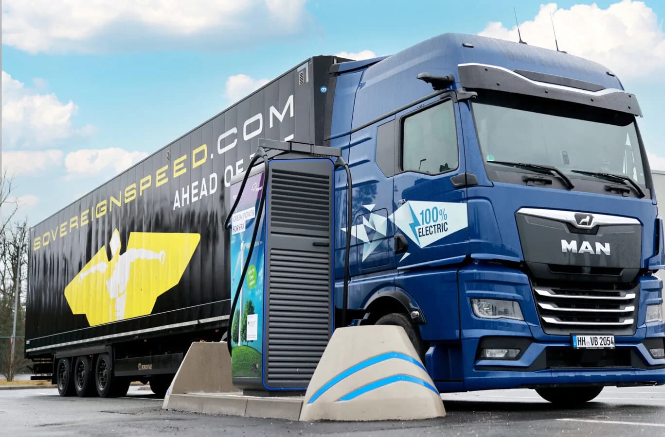 Blauer MAN Sattelzug mit Anhänger „sovereignspeed.com“ und 100% electric Aufschrift an einer Fraport ePark Lkw-Ladestation beim Laden
