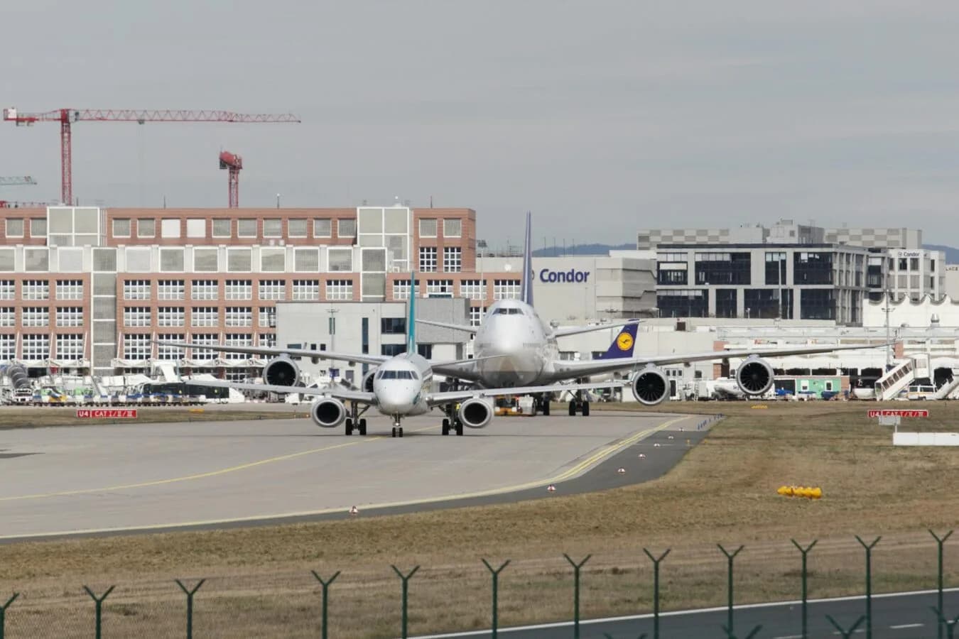 Flughafenvorfeld mit wartenden Großraumflugzeugen in Taxibahnreihe, Lufthansa und Condor Marken sichtbar, Terminalgebäude und Bodenverkehrsdienste, Verkehrszahlen Fraport Januar