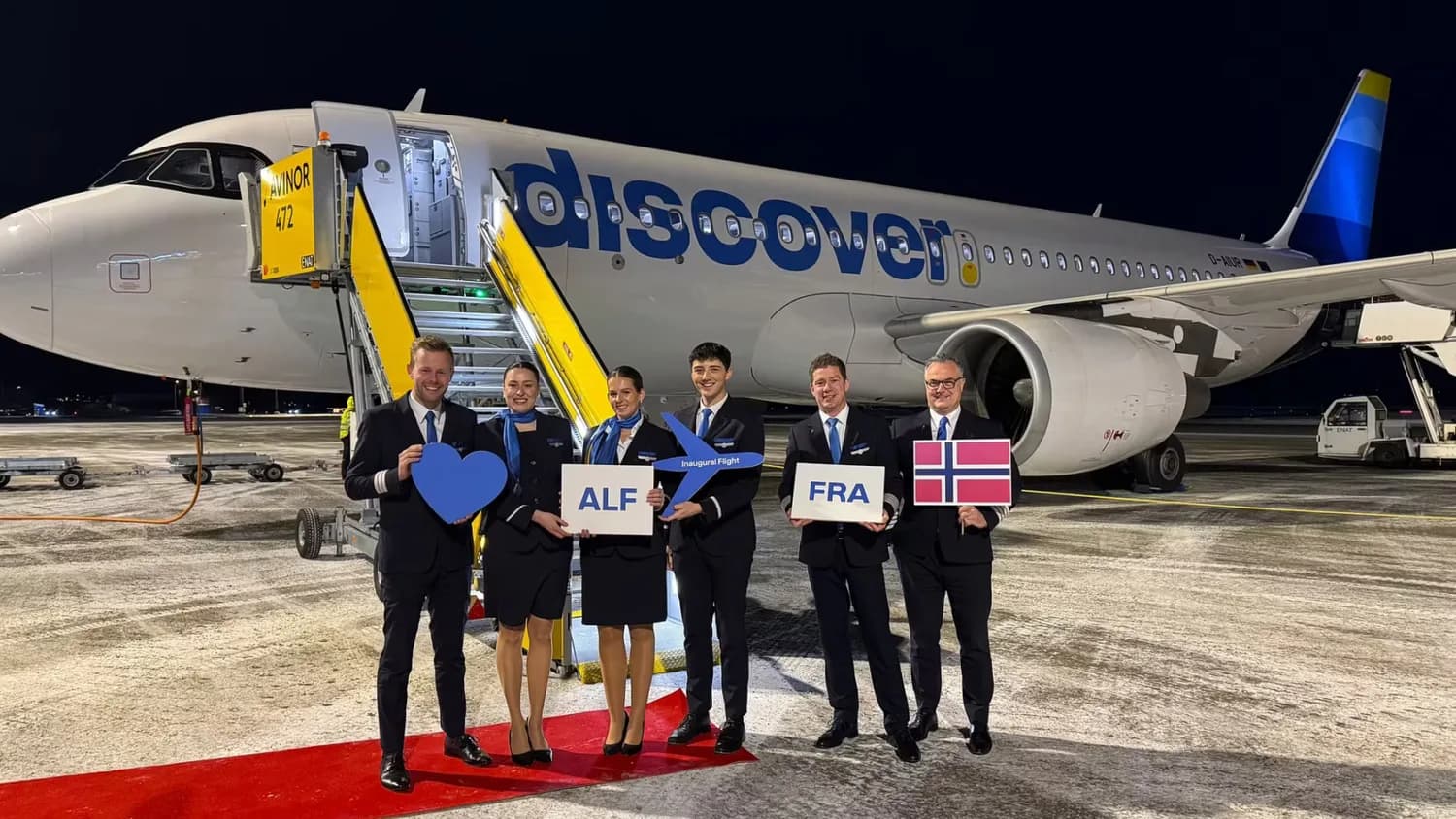 Crew vor einem Discover Airlines Flugzeug am Flughafen Frankfurt bei Nacht mit Willkommensschildern ALF und FRA und norwegischer Flagge