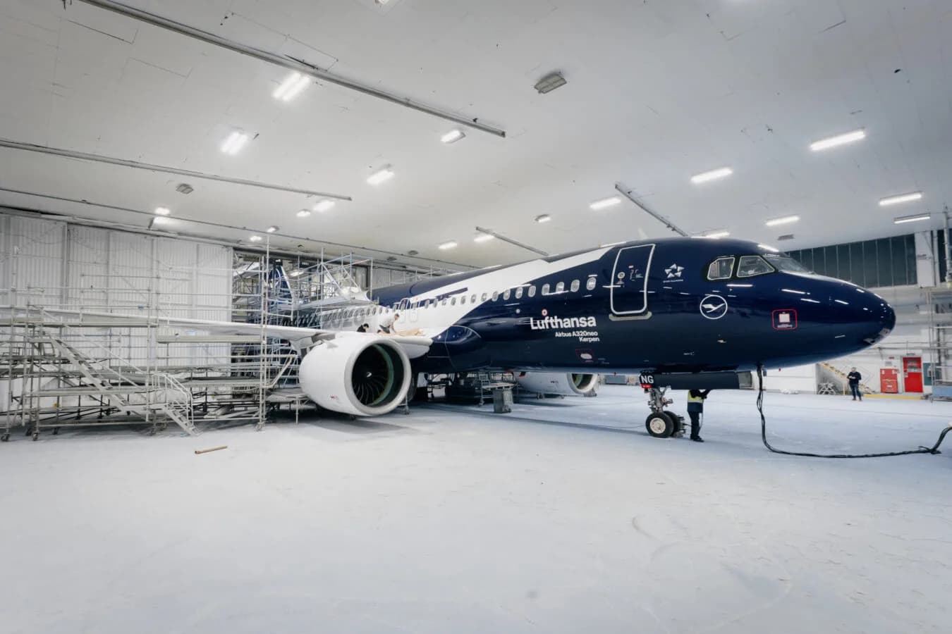 Lufthansa Airbus A320neo in spezieller Lackierung in einer Hangarhalle neben Gerüsten und Wartungsequipment