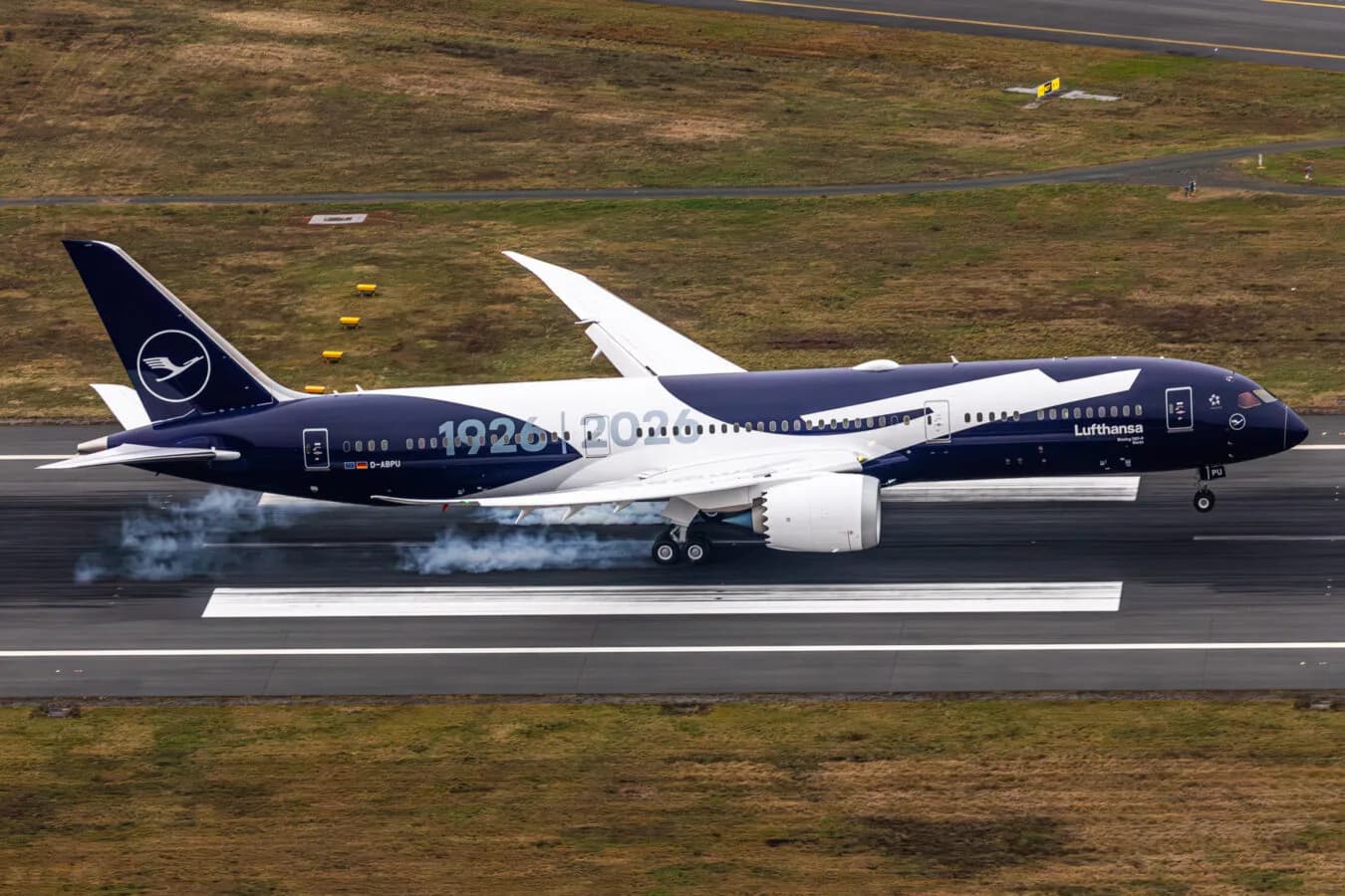 Boeing 787 in dunkelblauer Sonderlackierung mit großem Kranich-Logo und Kennung D-ABPU bei der Landung auf der Landebahn