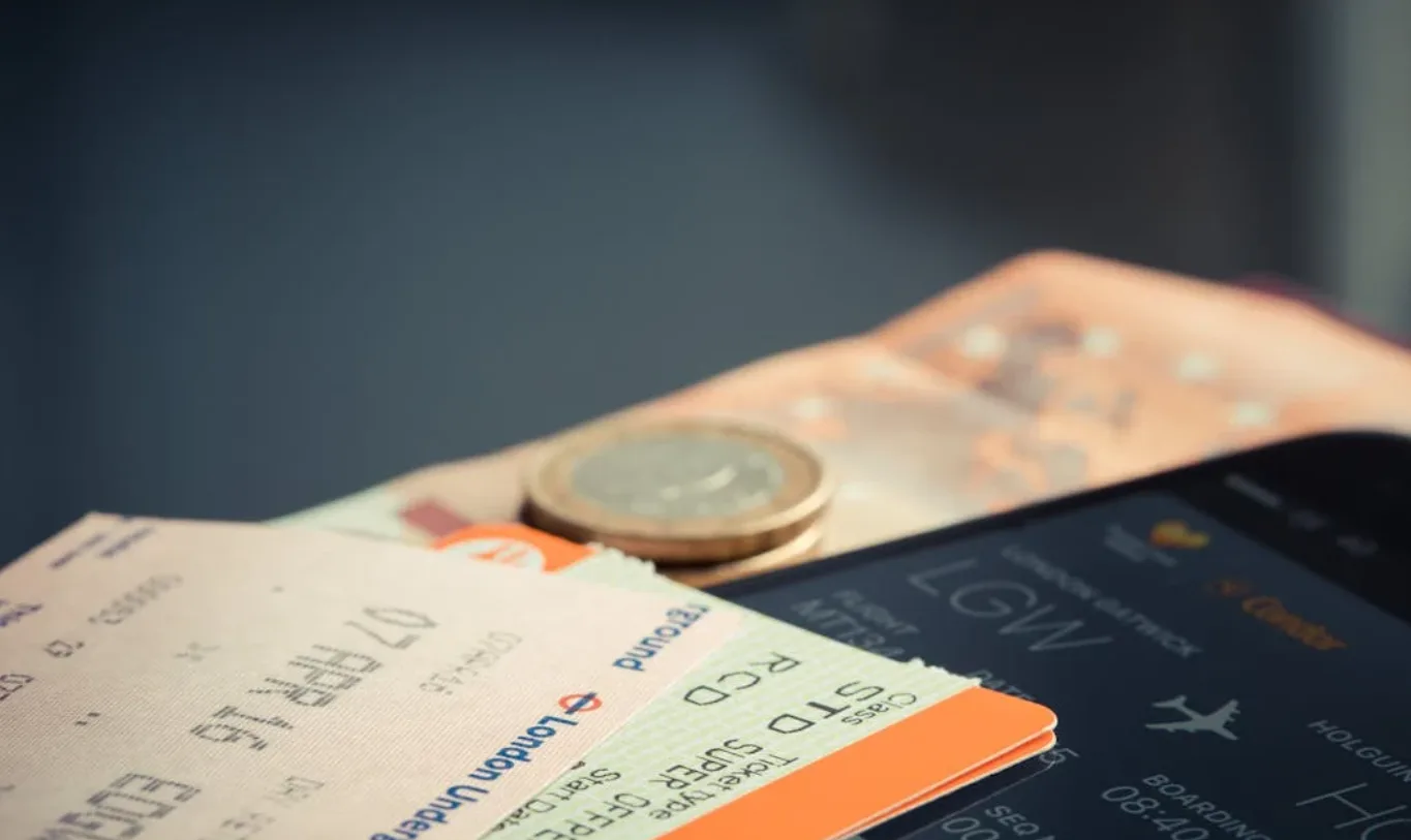 Flugtickets, Euromünzen und Smartphone mit Reiseinformationen als Symbol für Fraport Dividende 1 Euro