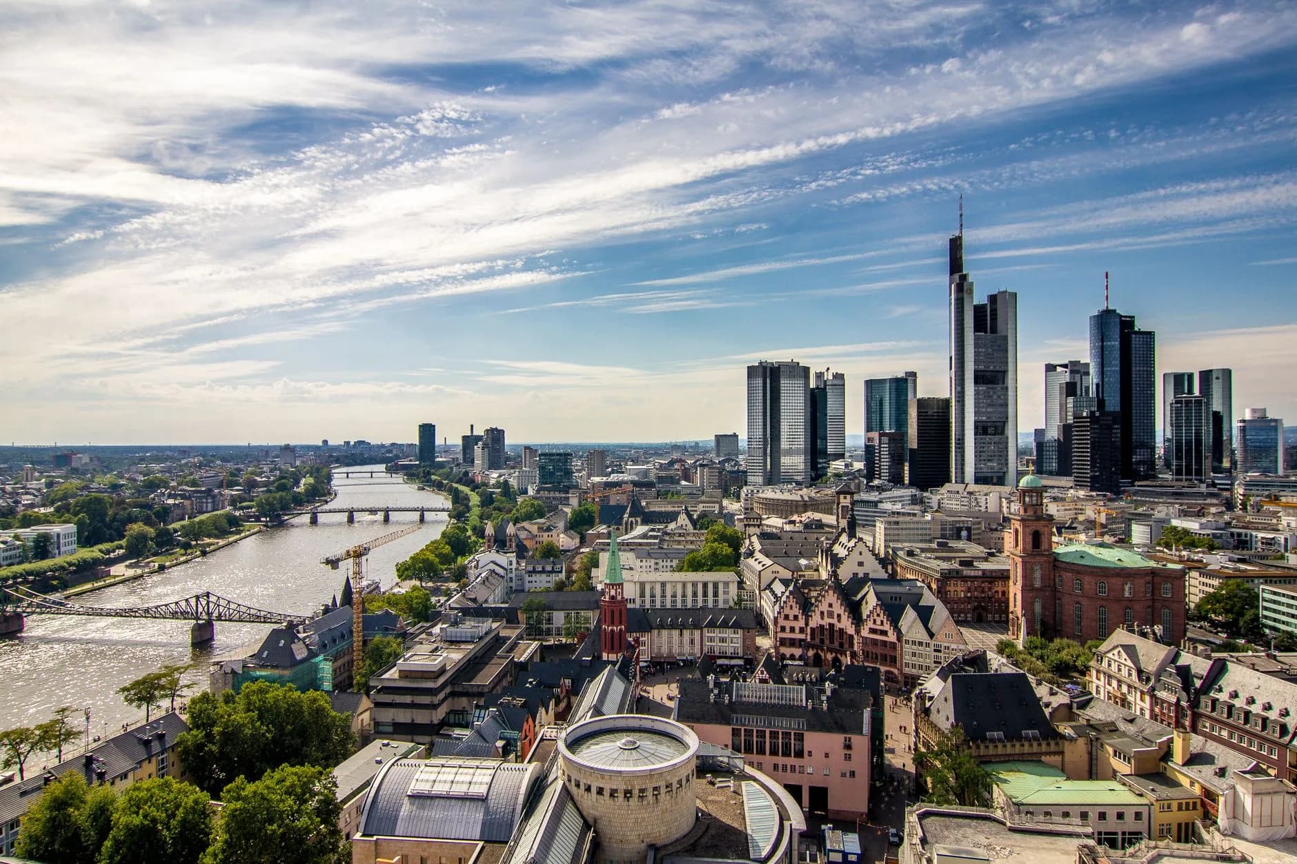 Blick über die Frankfurter Altstadt und den Main auf die Skyline mit Hochhäusern bei strahlendem Sonnenschein