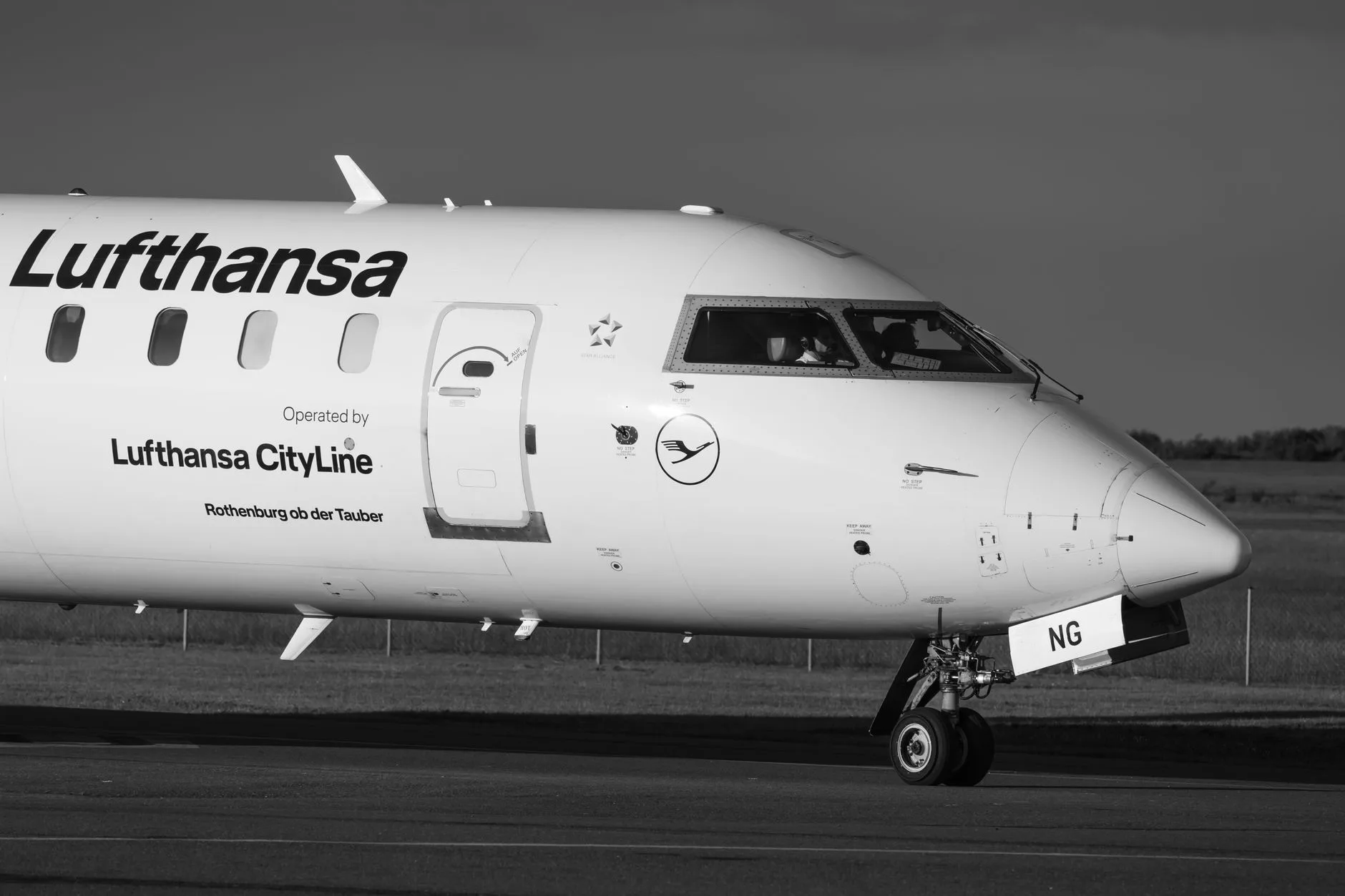Lufthansa CityLine Flugzeug mit Cockpit und Bugrad rollt auf dem Rollfeld, Schwarz-Weiß-Aufnahme