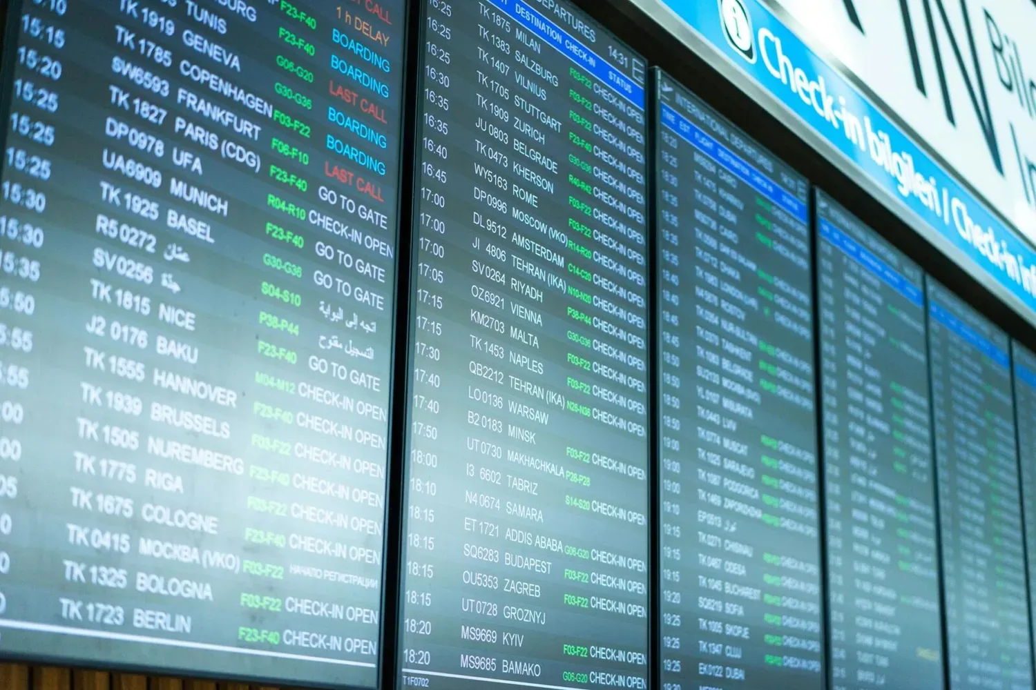 Anzeigetafel am Flughafen mit Abflugzeiten, Zielen und Status wie Boarding und Check-in Open