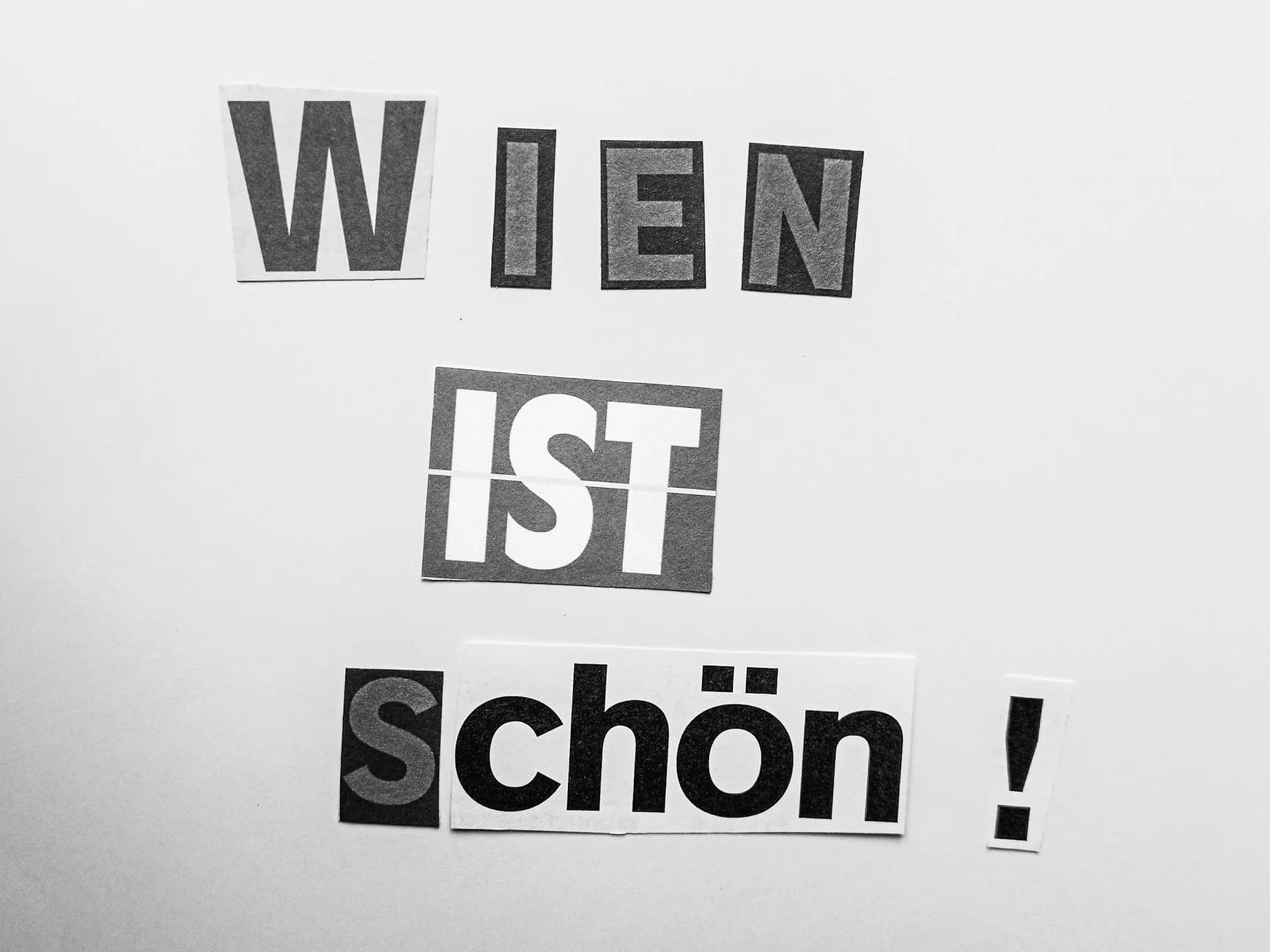 Ausgeschnittene Buchstaben aus Zeitungspapier bilden den Schriftzug Wien ist schön auf weißem Untergrund