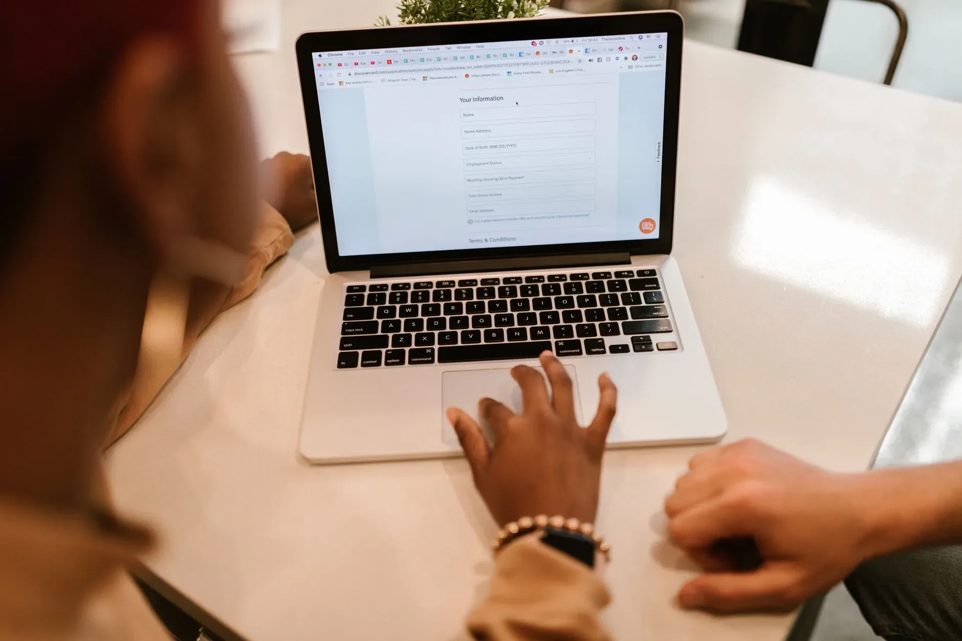 Person tippt am Laptop ein Online-Formular mit persönlichen Daten aus