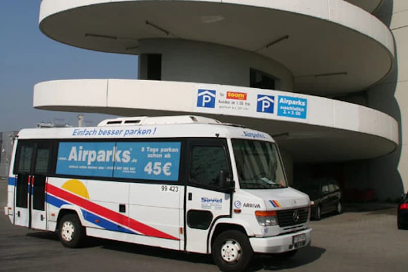 Shuttlebus mit Airparks Werbung vor spiralförmiger Zufahrt eines Parkhauses am Flughafen Frankfurt.