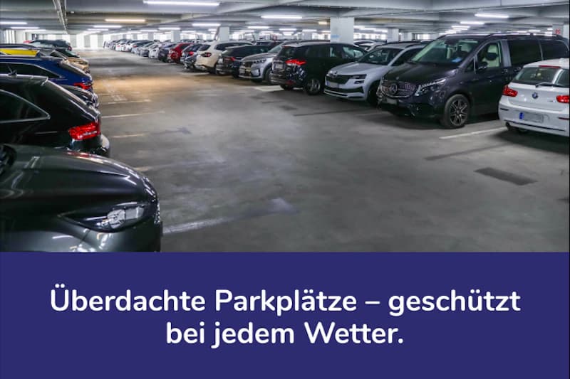 Überdachtes Parkhaus mit zwei Reihen geparkter Autos und Deckenbeleuchtung.