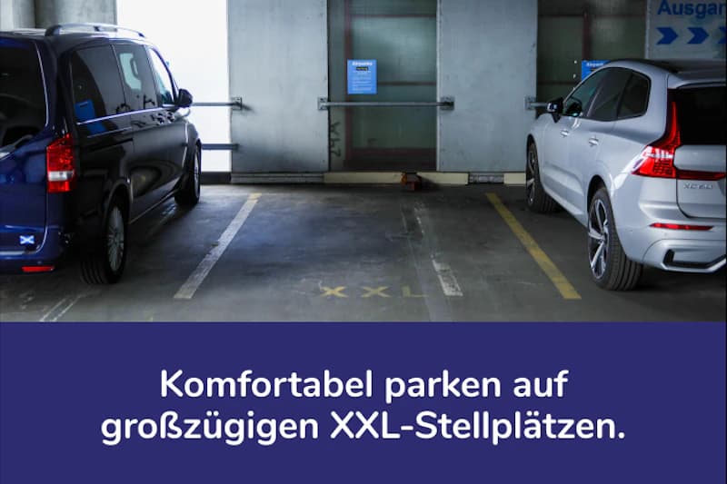Parkebene im Parkhaus mit leerem XXL-Stellplatz zwischen zwei geparkten Fahrzeugen und Wand mit Hinweisschild.