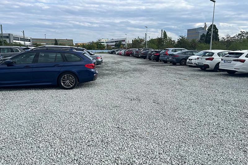Kieselparkplatz mit Reihen geparkter Autos und Laternen am Flughafen Frankfurt.