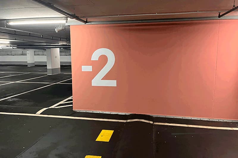 Tiefgaragenebene mit großer weißer Beschriftung -2 auf orange Wand, Parkflächen und gelbe Bodenmarkierungen.