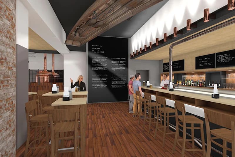 Hotelbar mit Holzfußboden, langer Theke, Barhockern, Gästen und Schiefertafeln an der Wand.