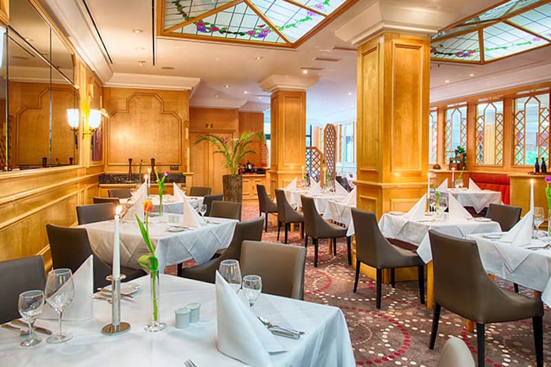 Eingerichtetes Restaurant mit weißen Tischdecken, Kerzen und Holzsäulen.