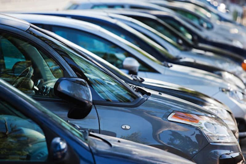 Reihe geparkter Autos seitlich aufgenommen mit sichtbaren Vorderseiten und Außenspiegeln.