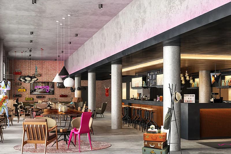 Offener Hoteltheken- und Aufenthaltsbereich mit Säulen, Theke, Sitzgruppen und Neonleuchtschrift moxy an Backsteinwand.