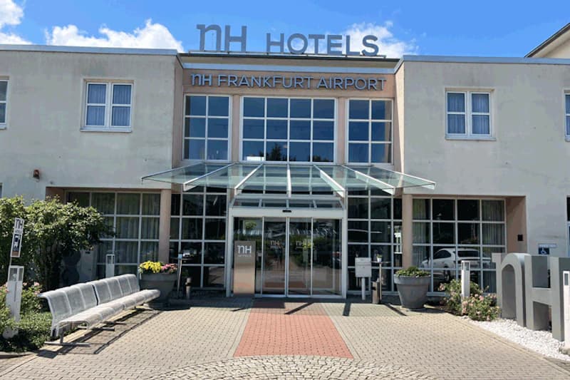 Haupteingang des NH Frankfurt Airport mit Glasvordach, Schiebetüren und Hotelbeschriftung oberhalb.