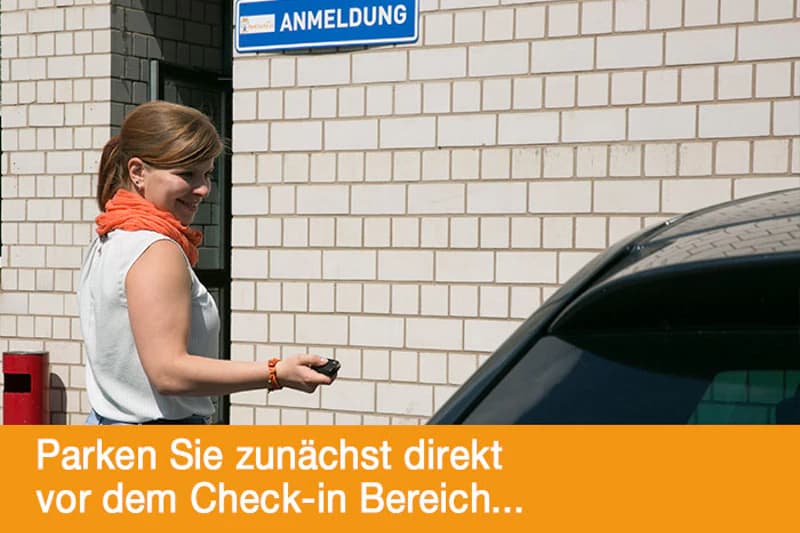 Frau mit Autoschlüssel neben Auto vor heller Klinkerwand mit Schild Anmeldung.