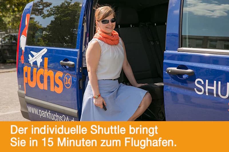 Frau mit Sonnenbrille und orangefarbigem Schal sitzt im offenen blauen Transferbus mit Parkfuchs24 Schriftzug.