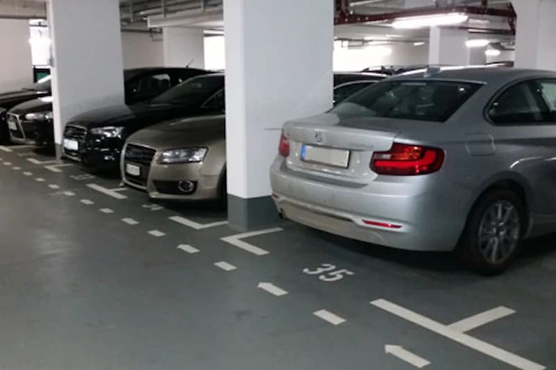 Gedecktes Parkdeck mit mehreren geparkten Autos, Säulen und markierten Stellplätzen, sichtbare Nummer 35.