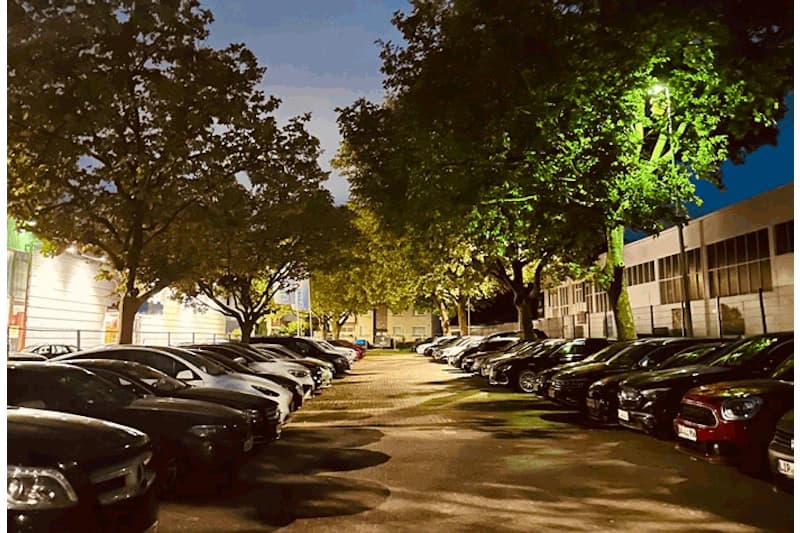 Drei geparkte Autos nachts vor einem Gewerbegebäude, darunter der Schriftzug Überwachung.