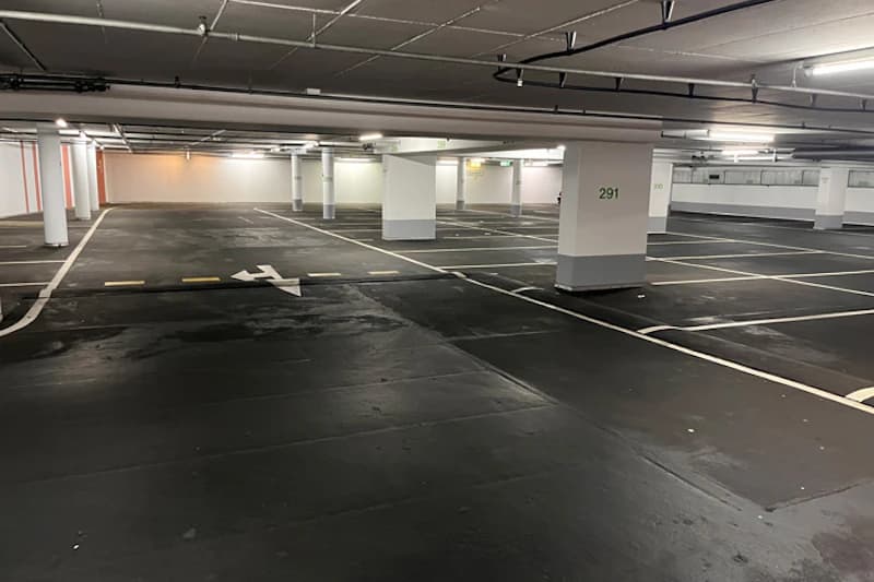 Leere Tiefgarage mit markierten Parkplätzen, Bodenpfeil und nummerierter Säule 291.