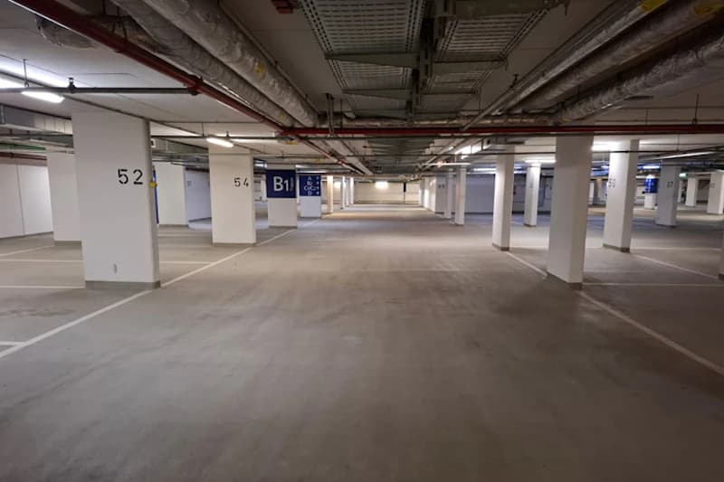 Leere Tiefgarage mit markierten Stellplätzen und Säulen, Ebene B1 sowie Säulenkennzeichnungen 52 und 54 sichtbar.