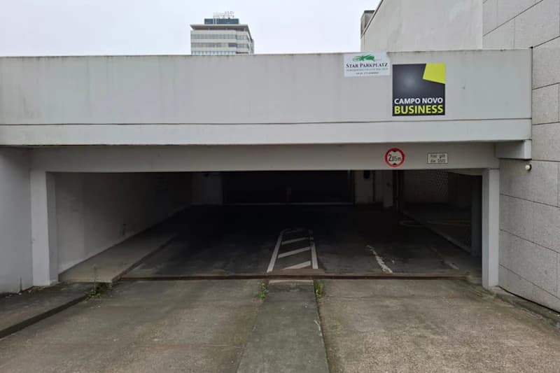 Tiefgarageneinfahrt mit niedriger Decke, Fahrspurmarkierung und Schild Höhenbegrenzung 2,0 m; Campo Novo Business Schild oben.