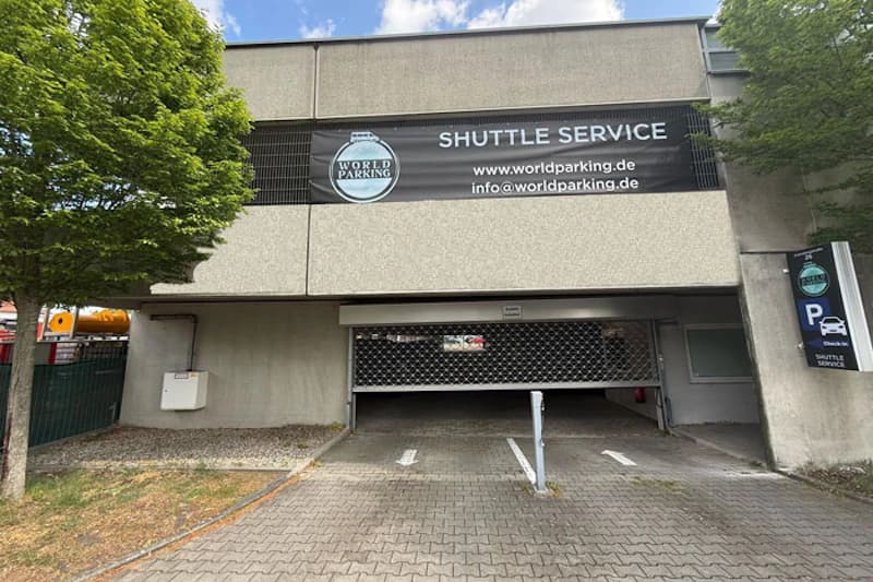Parkhauszufahrt mit geschlossenem Rollgitter, Banner mit World Parking-Logo und Hinweis auf Pendelverkehr.