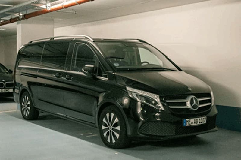 Schwarzer Mercedes-Van in beleuchteter Tiefgarage neben weißer Wand.